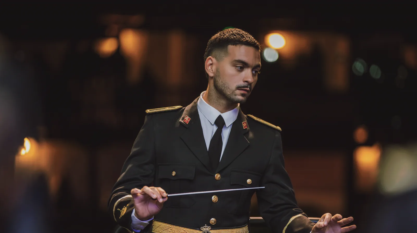 Javier Cebrero dirige, batuta en mano, con el uniforme de gala